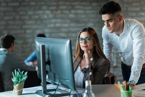 Two young entrepreneurs working on a computer and reading an e-mail in the office.